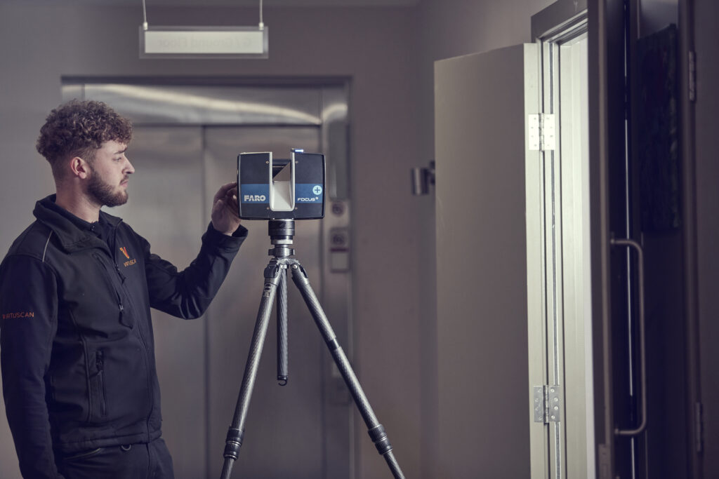 A Virtuscan employee standing in front of a camera on a tripod, choosing the best area for BIM.