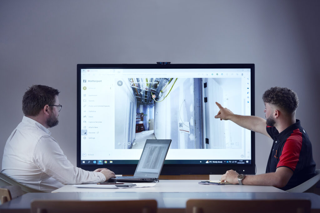 Two Virtuscan employees discussing fire strategy on laptop screen.